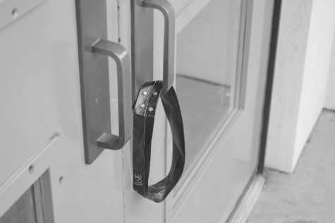 The main building door closest to the gym (and others like it) has been fitted with a band to aid those who normally have trouble opening the door. This band has been labeled with a statement Do Not Remove This Strap as a way to deter the loss of the strap. 