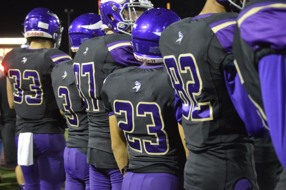 Puyallup Vikings substitutes lined up out of bounds waiting to be called onto the field by a coach.  